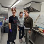 Drei Helfer beim Plätzchen backen in der Küche mit weihnachtlichem Haarschmuck